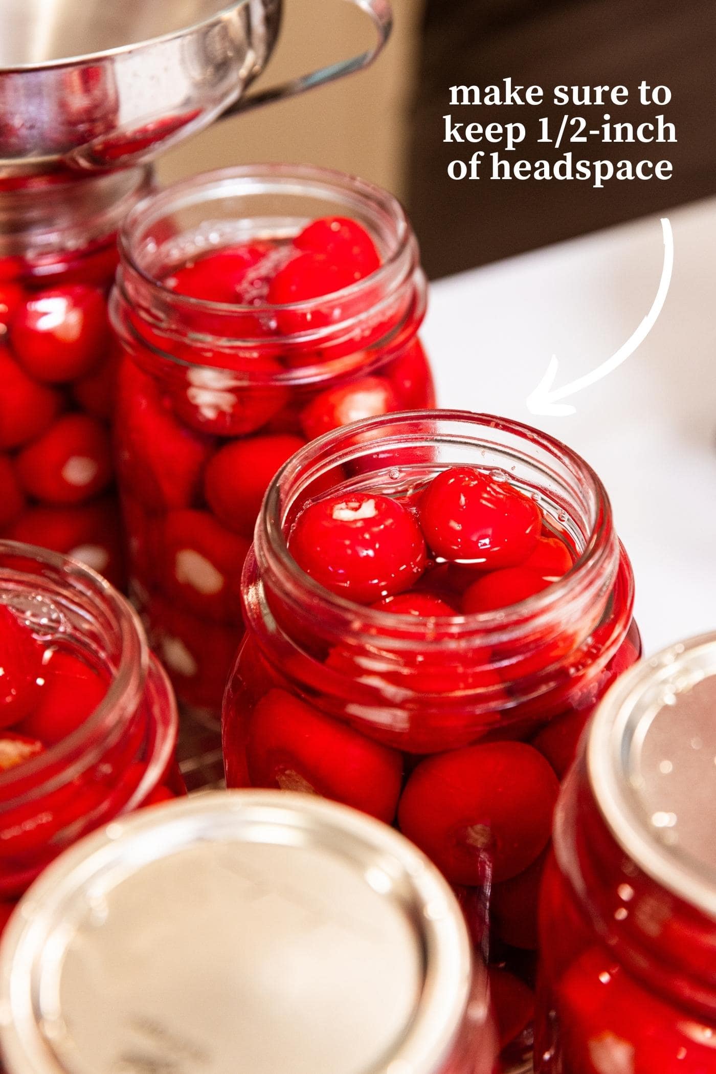 Glass canning jars filled with small red sweet peppers with text stating to keep a certain distance empty at the top of the jar.