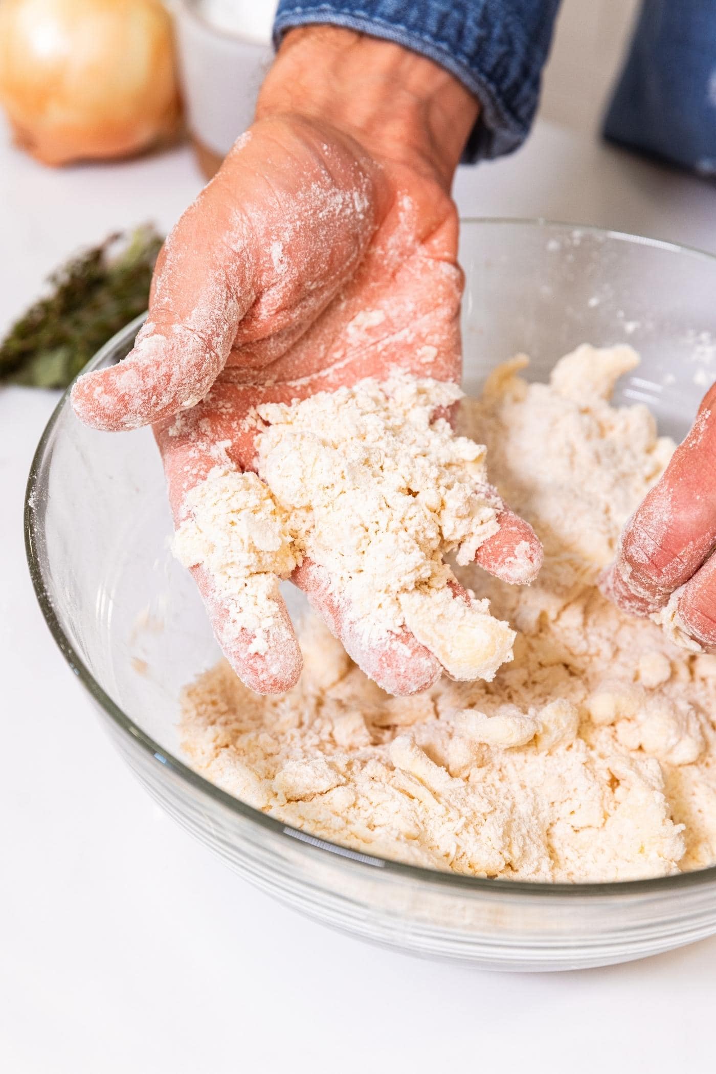 Hand showing how dough falls apart after being lightly touched after being pushed together into a fistful.