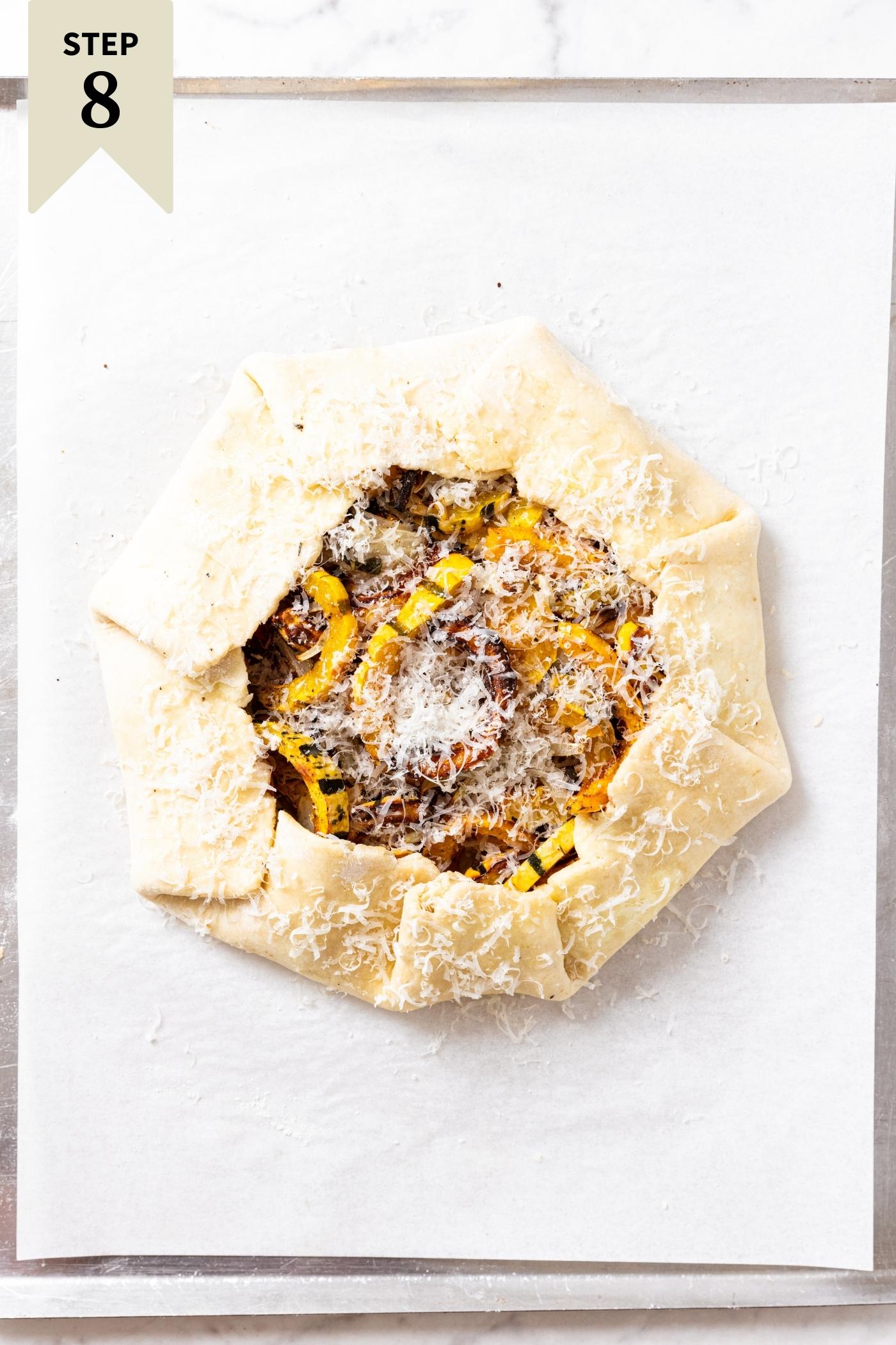 Unbaked roasted squash galette sitting on piece of parchment on baking sheet before going into the oven.