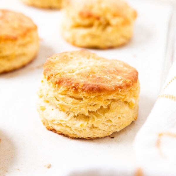 White parchment-lined baking sheet filled with baked buttermilk biscuits showing flaky interiors.