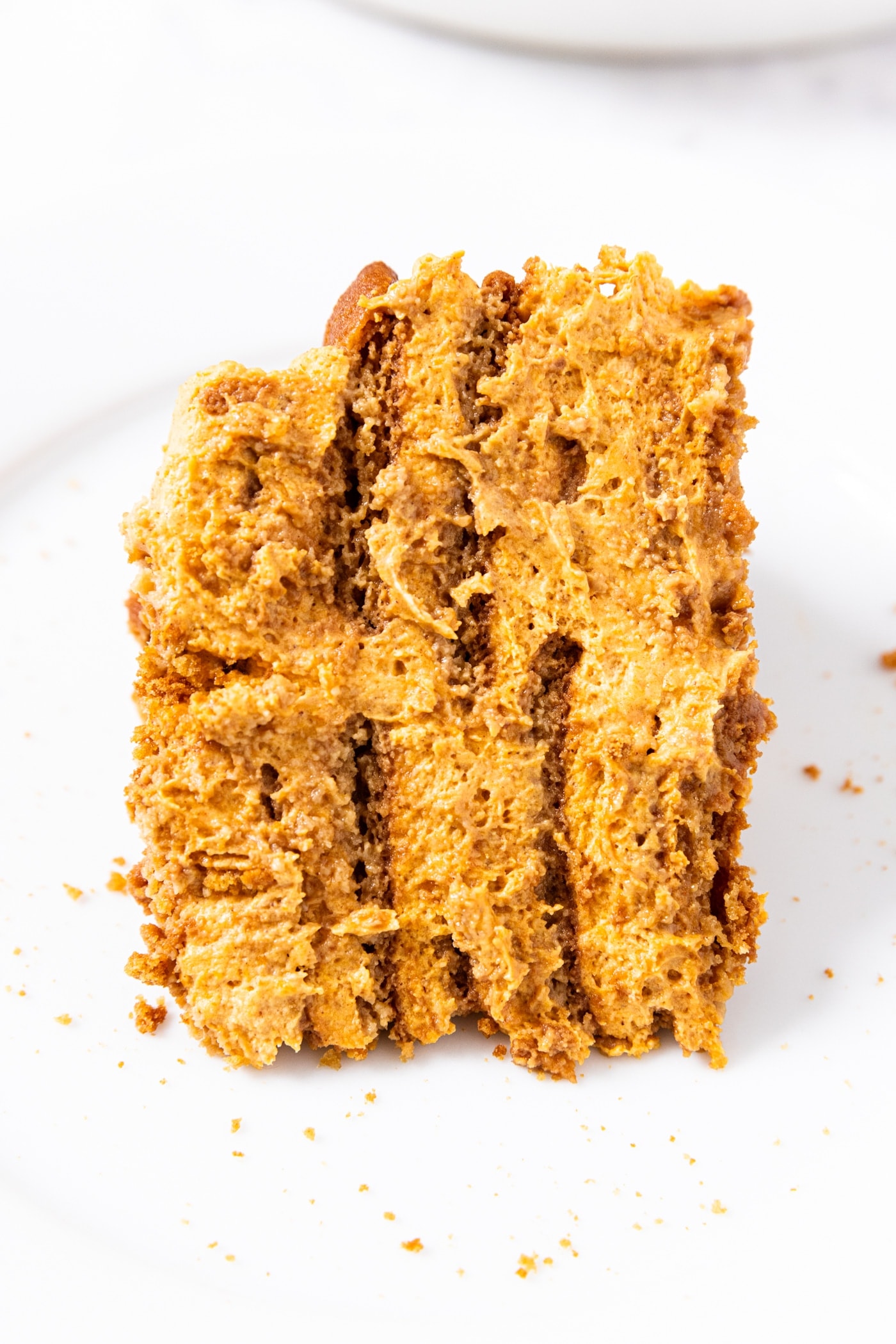 White plate with piece of pumpkin icebox cake showing multiple layers of pumpkin and gingersnap cookies.