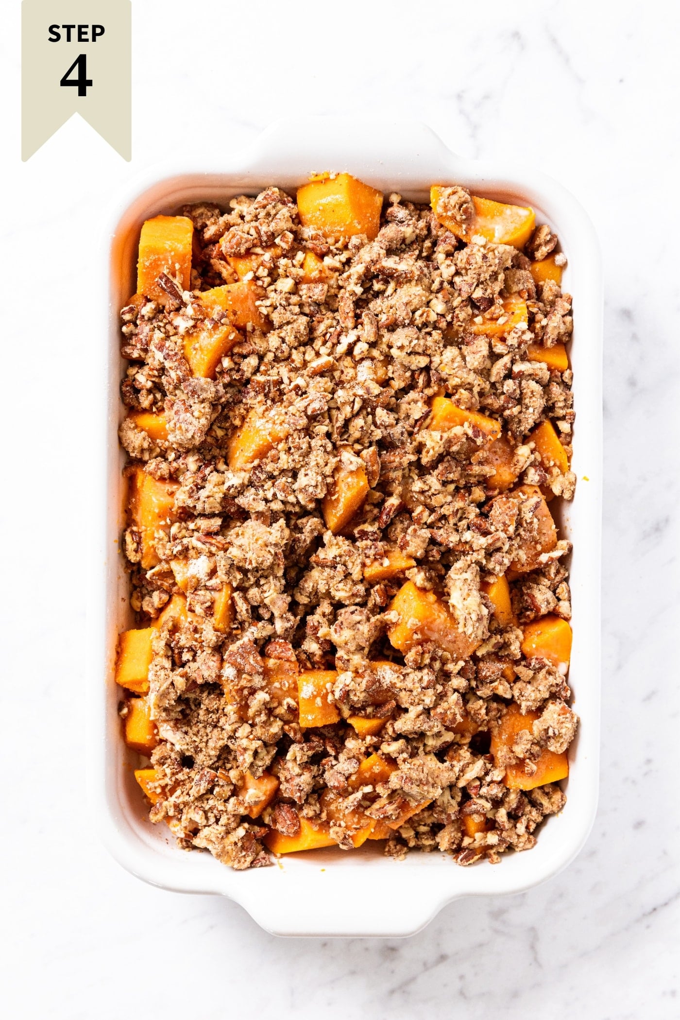 White baking dish filled with unbaked sweet potato casserole topped with pecan streusel topping right before going into the oven.
