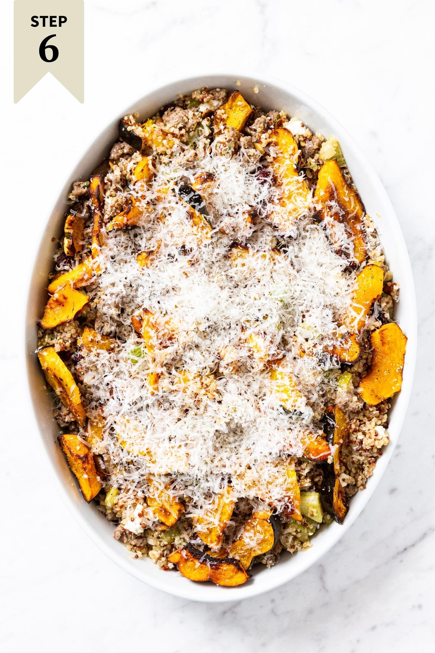 White baking dish with unbaked stuffed acorn squash casserole mixture topped with Parmesan cheese sitting on marble surface.