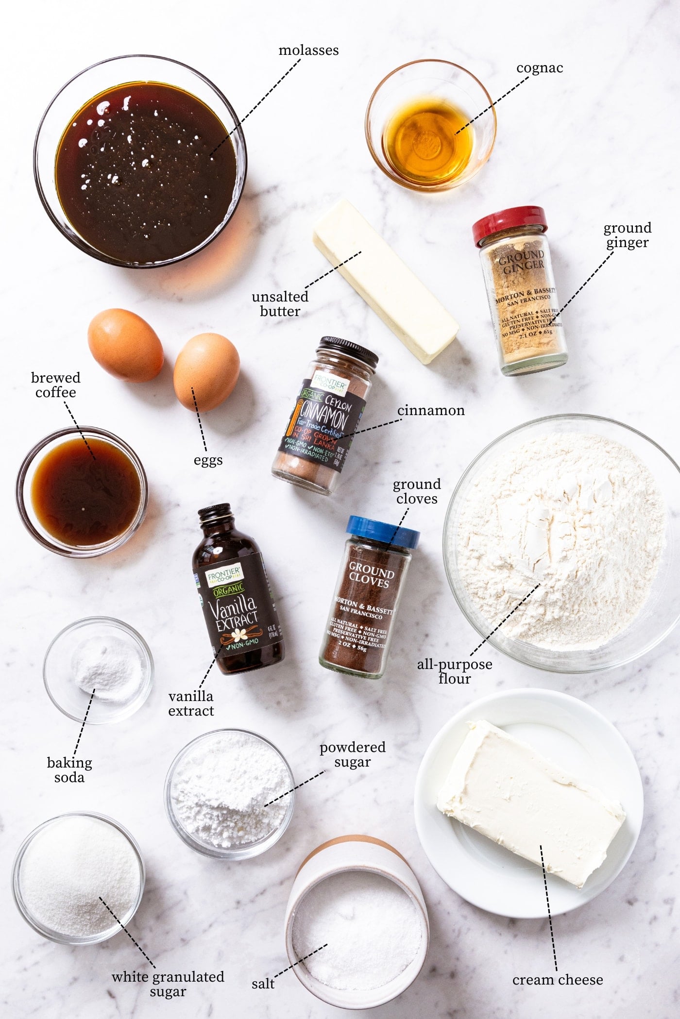 White marble surface filled with all of the ingredients needed to make a gingerbread spice cake including molasses, eggs, spices, flour, sugar, coffee, and more.