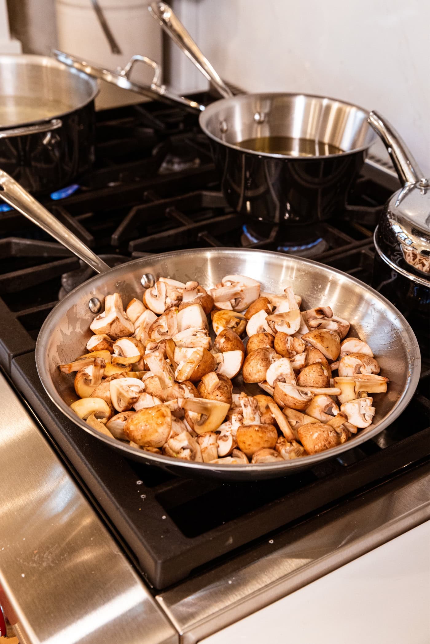 Uncooked mushrooms after being added to a stainless steel pan before starting to cook.