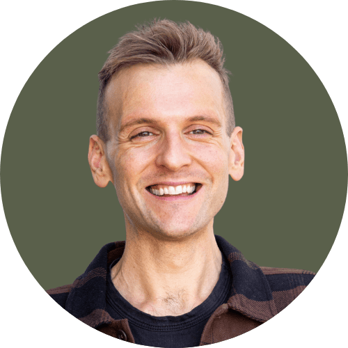 Kaleb Wyse wearing a brown and black plaid jacket standing in front of green background.