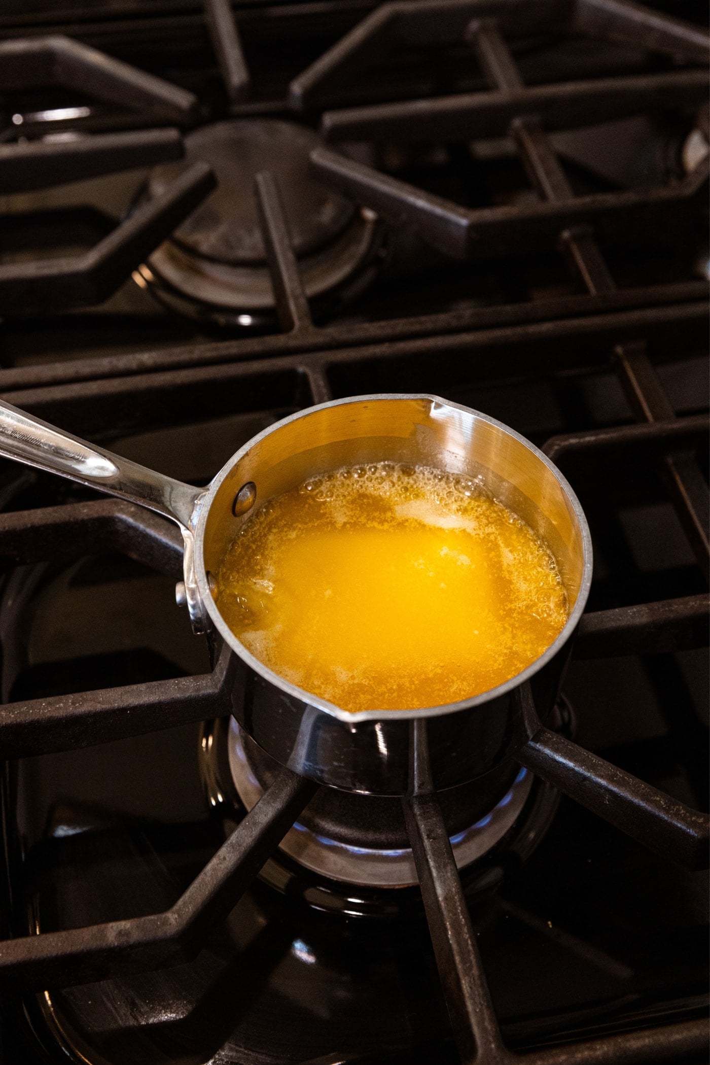 Small saucepan filled with melted butter sitting on stovetop after being heated into liquid form.