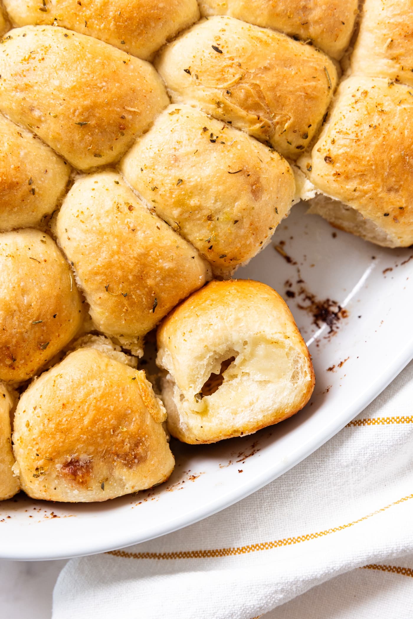 White oval baking dish filled with baked pizza buns with golden tops with one sitting on its side showing the interior texture.