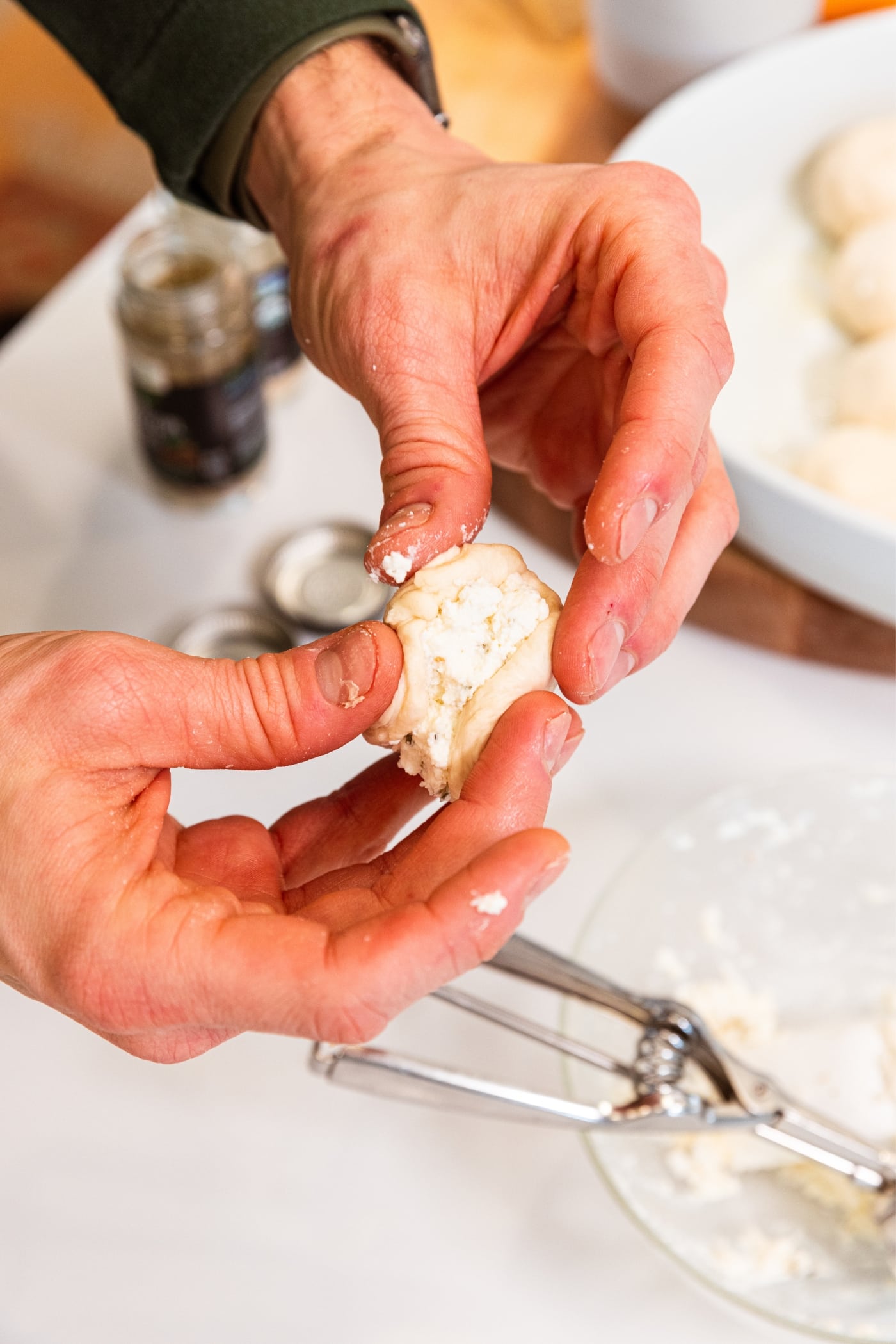 Hands squeezing together sides of pizza bite with ricotta cheese mixture inside.