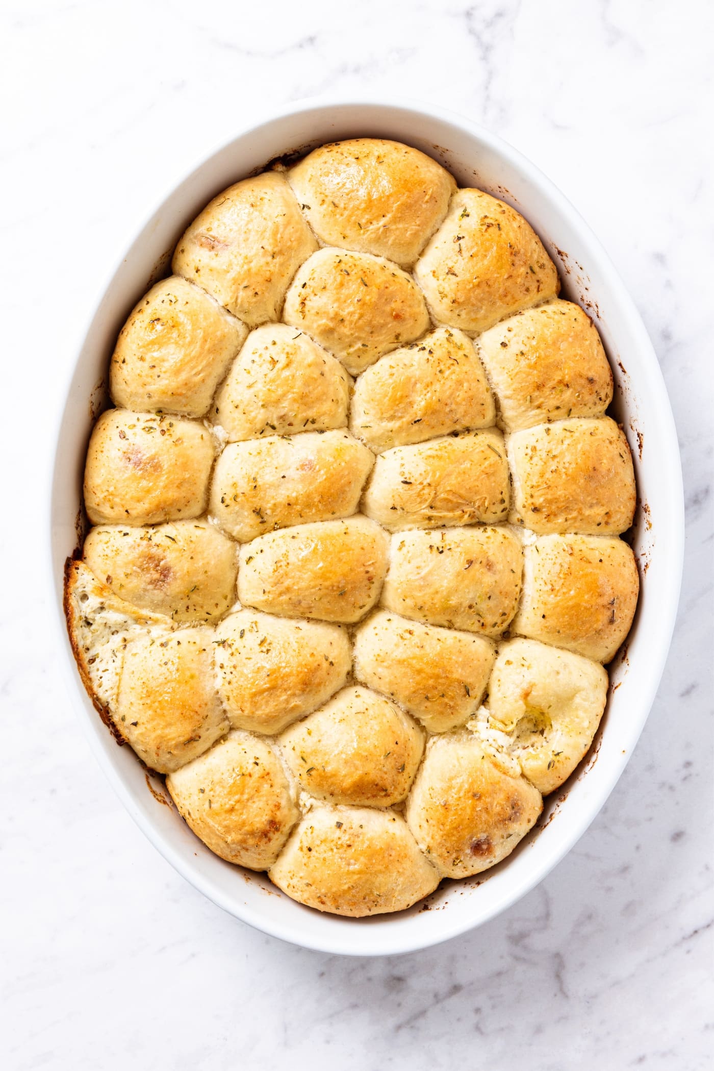 Oval white baking dish filled with baked pizza bites with golden topping.