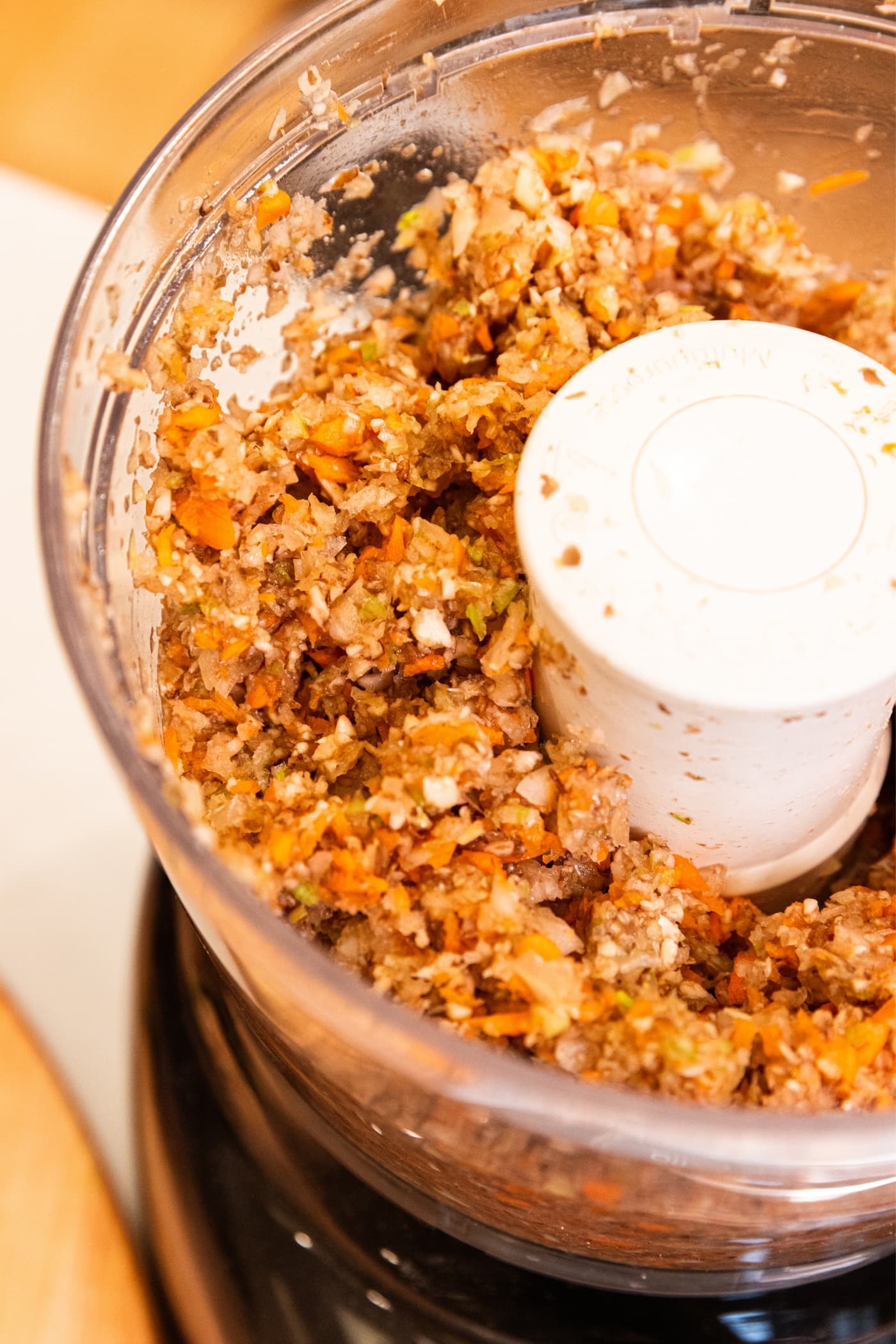 Processing container of food processor filled with chopped vegetables after being ground by blade.