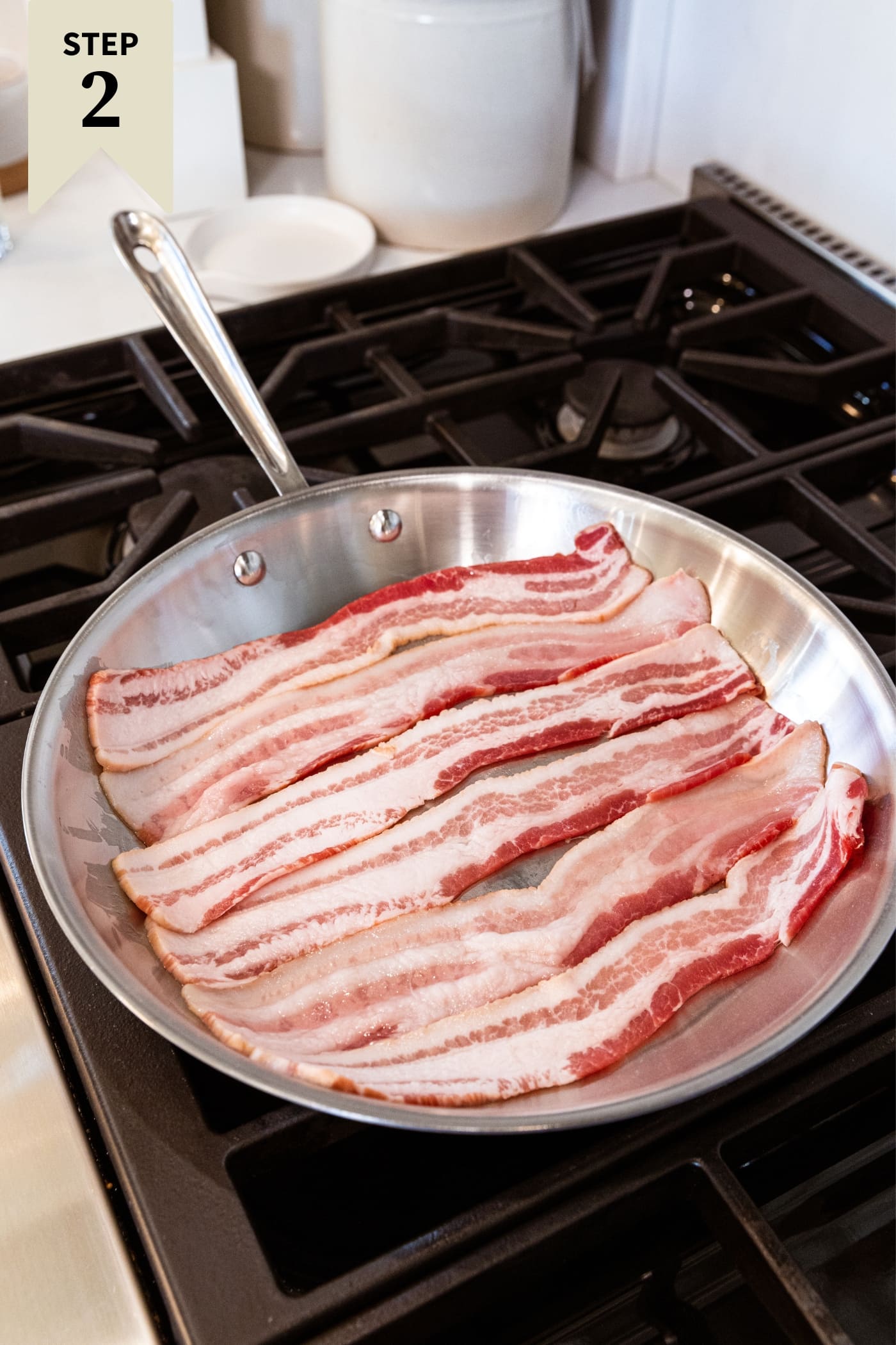 Skillet sitting on stovetop with raw pieces of bacon before being cooked.