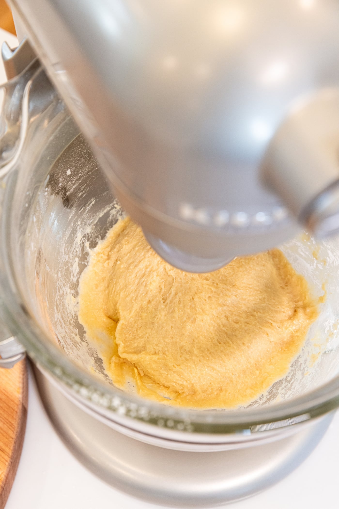 Stand mixer with glass bowl filled with cinnamon roll dough after being mixed together for a few minutes.