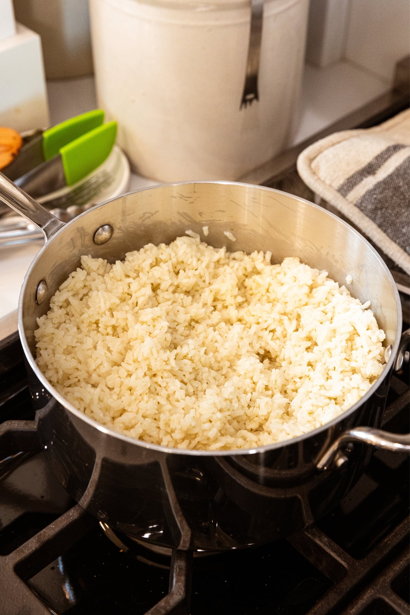 Cooked rice sitting in metal saucepan on stovetop after being fluffed.