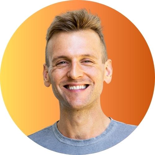 Kaleb Wyse wearing gray shirt standing in front of yellow to orange gradient background.