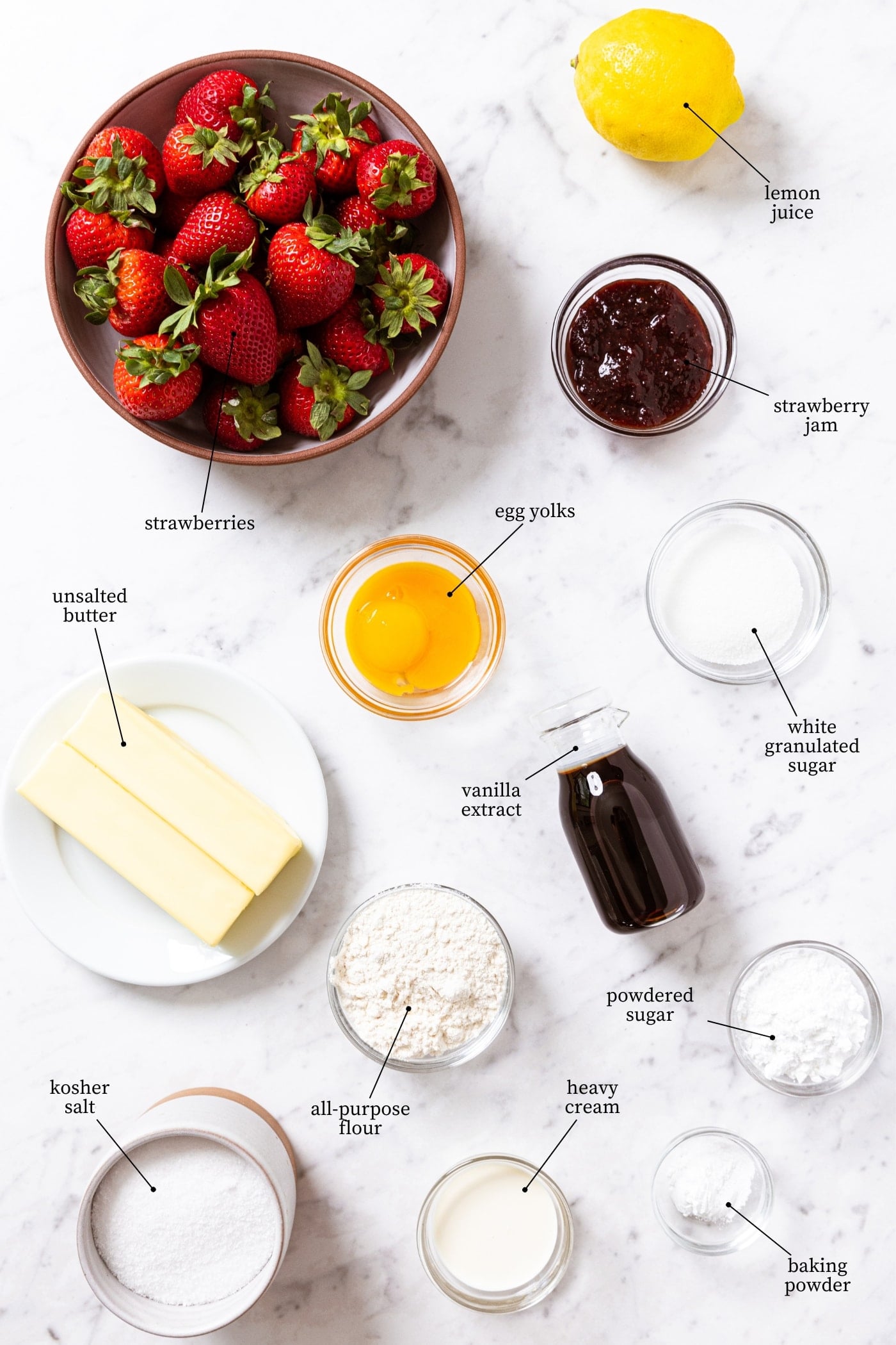 White marble surface filled with all ingredients needed to make strawberry crumb bars including strawberries, jam, butter, egg yolks, vanilla extract, sugar, flour, and more.