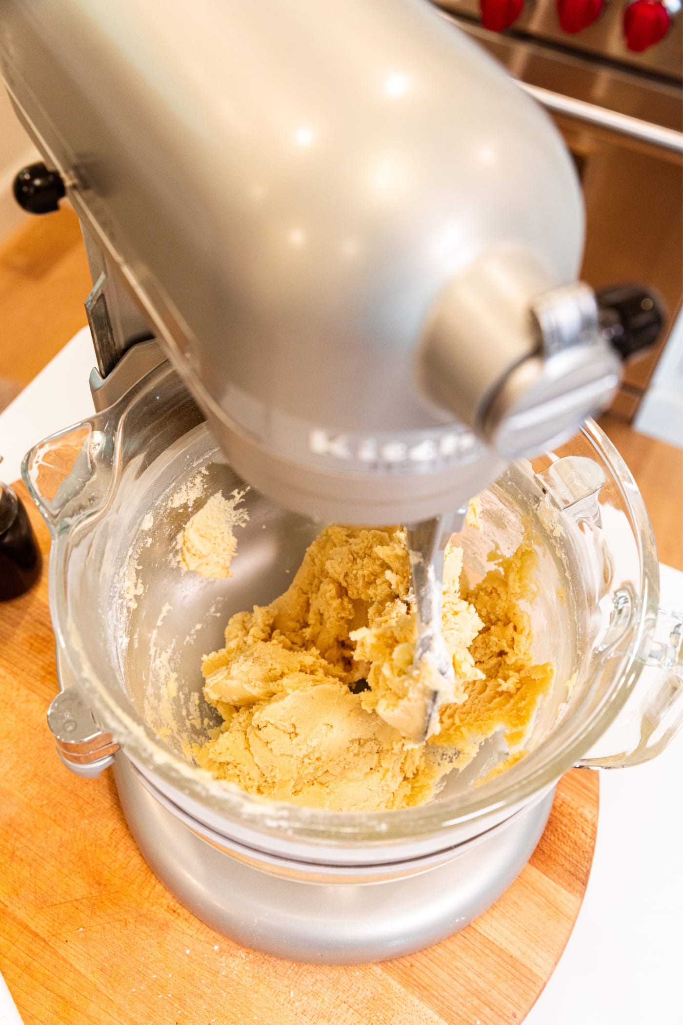 Stand mixer on countertop mixing together dry and wet ingredients for a crumbly dough.