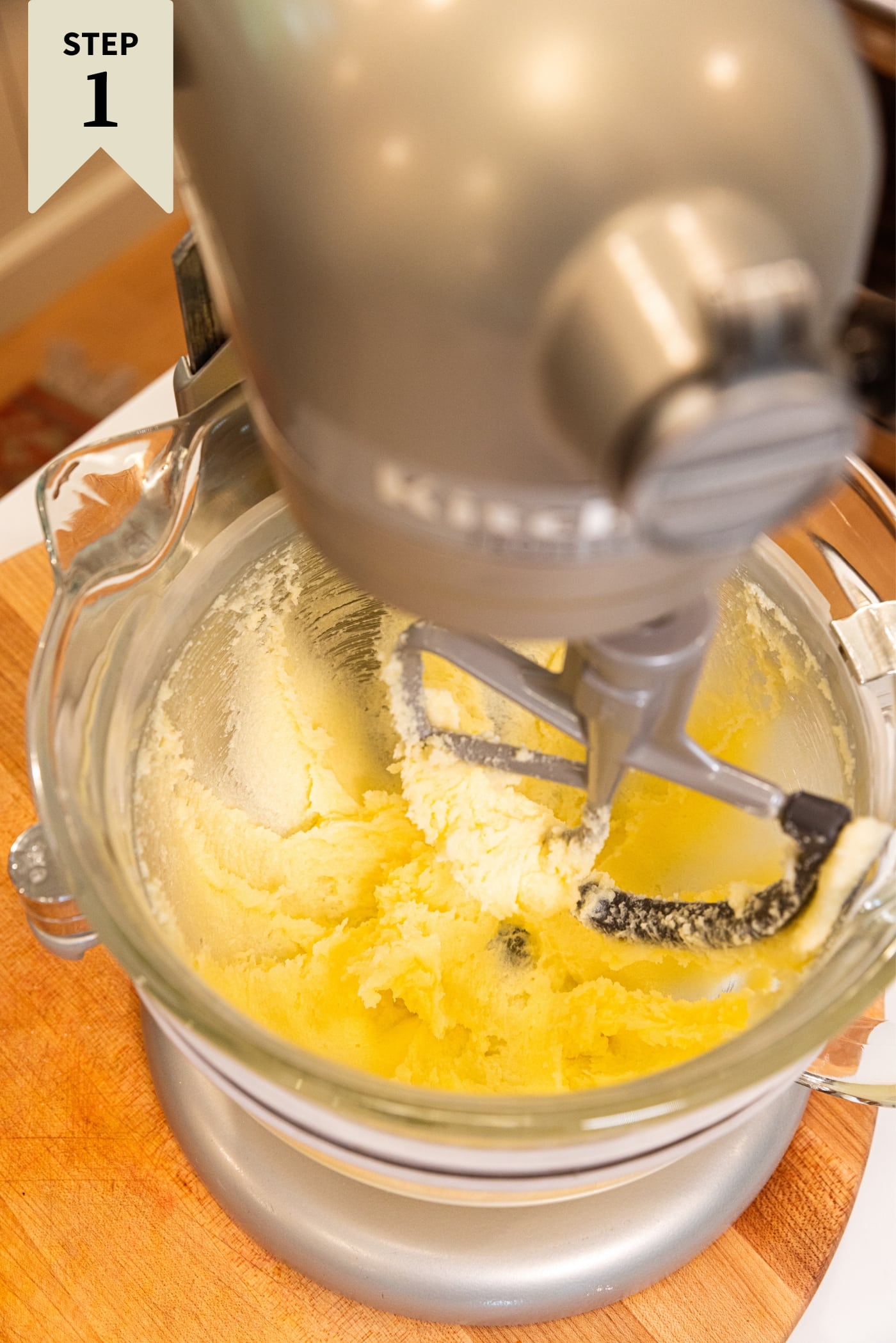 Stand mixer with glass bowl filled with creaming butter and sugar mixture.