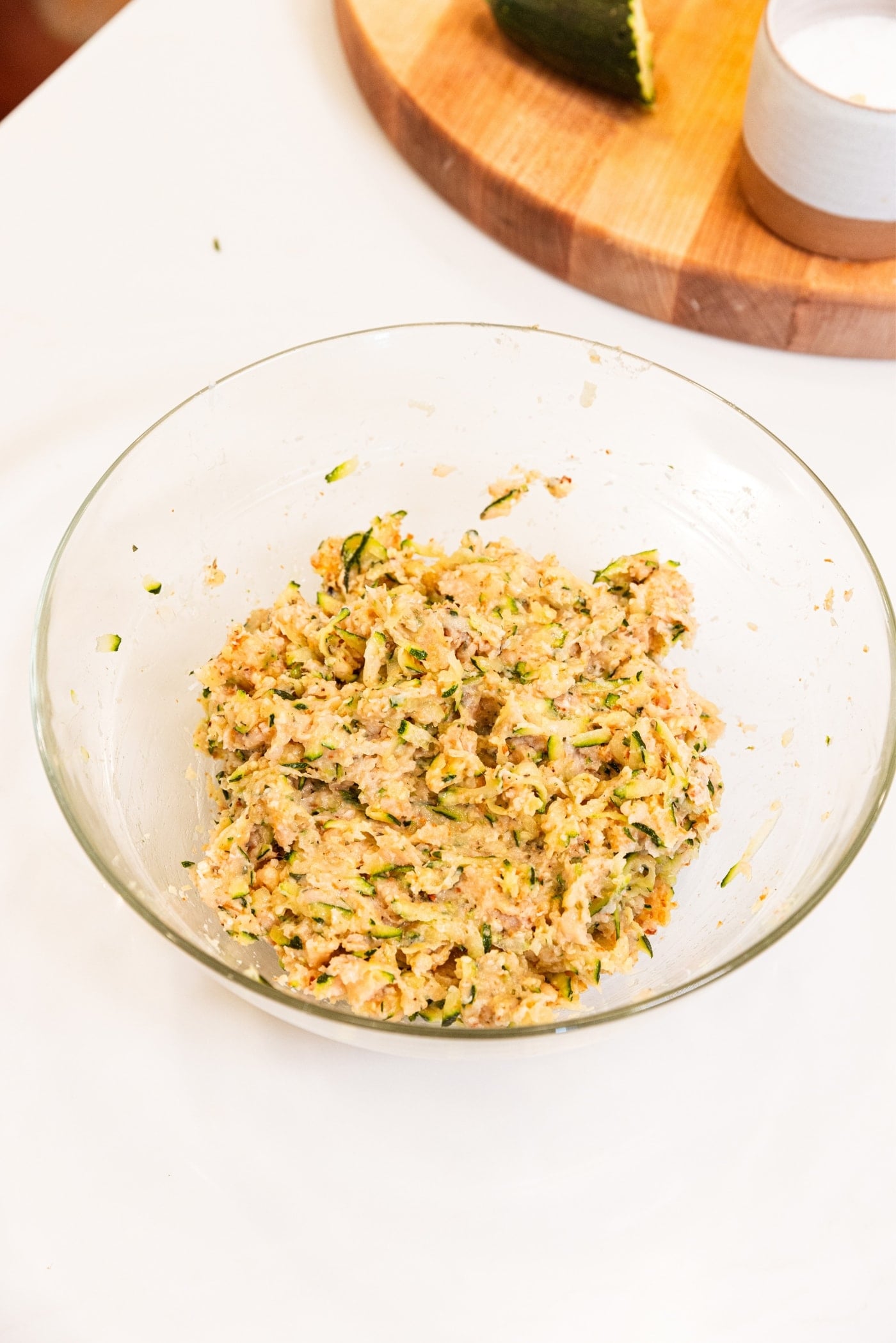 Mixed combination of chicken zucchini meatballs sitting in glass bowl on white countertop.