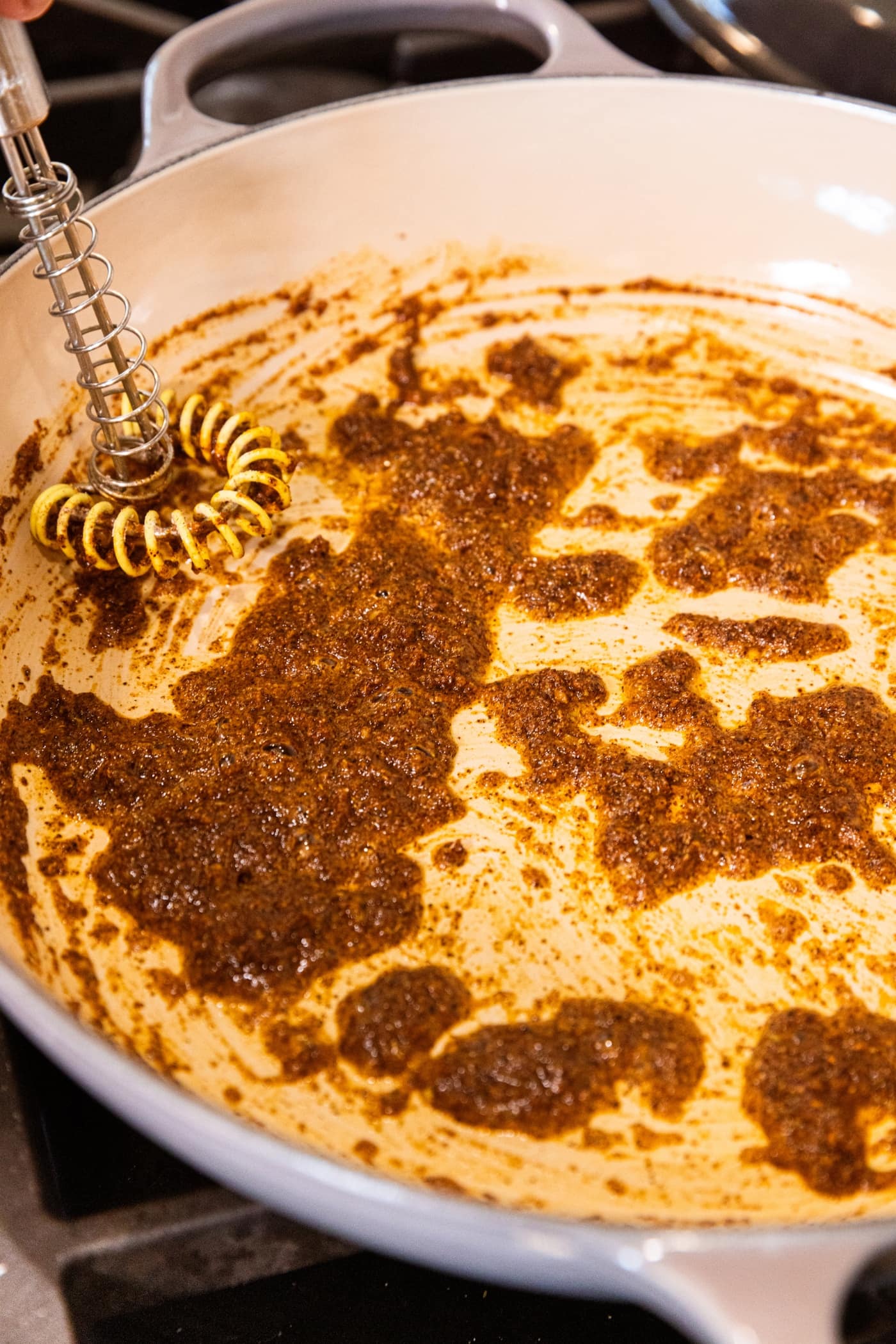Pot sitting on stovetop filled with sautéing mixture of flour and spices to make an enchilada sauce.