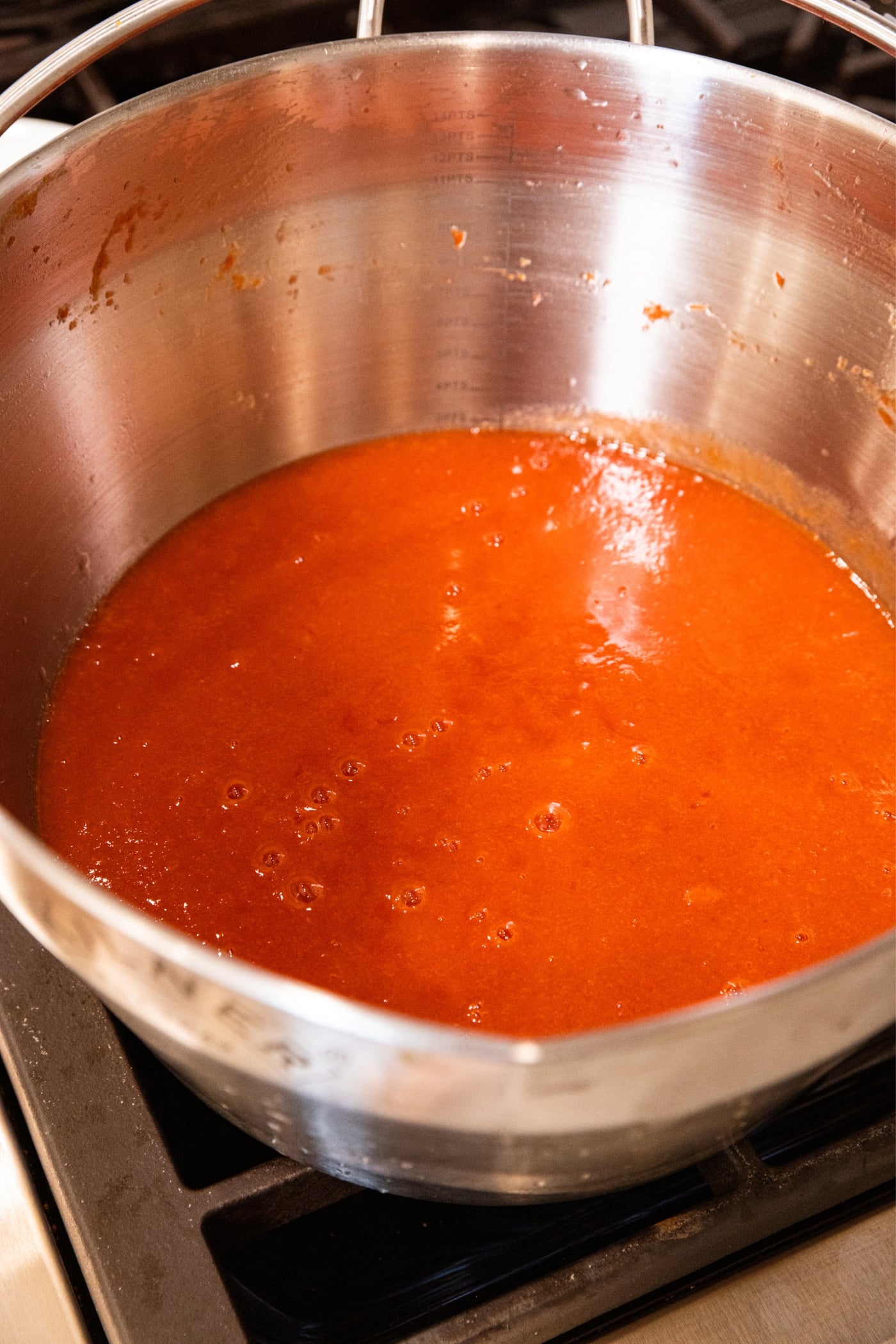 Large metal stockpot filled with strained peach juice set over the stovetop.