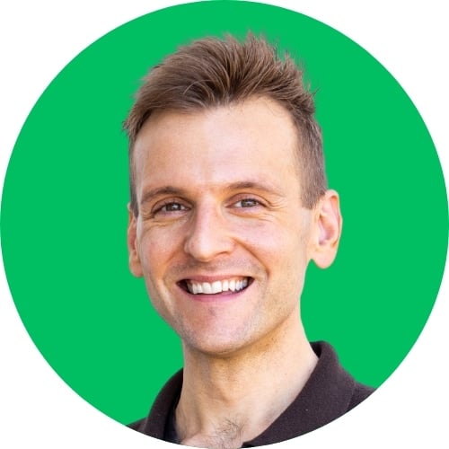 Kaleb Wyse wearing dark gray shirt standing in front of bright green background.