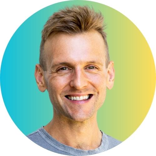 Kaleb Wyse wearing gray shirt smiling in front of gradient blue and yellow background.
