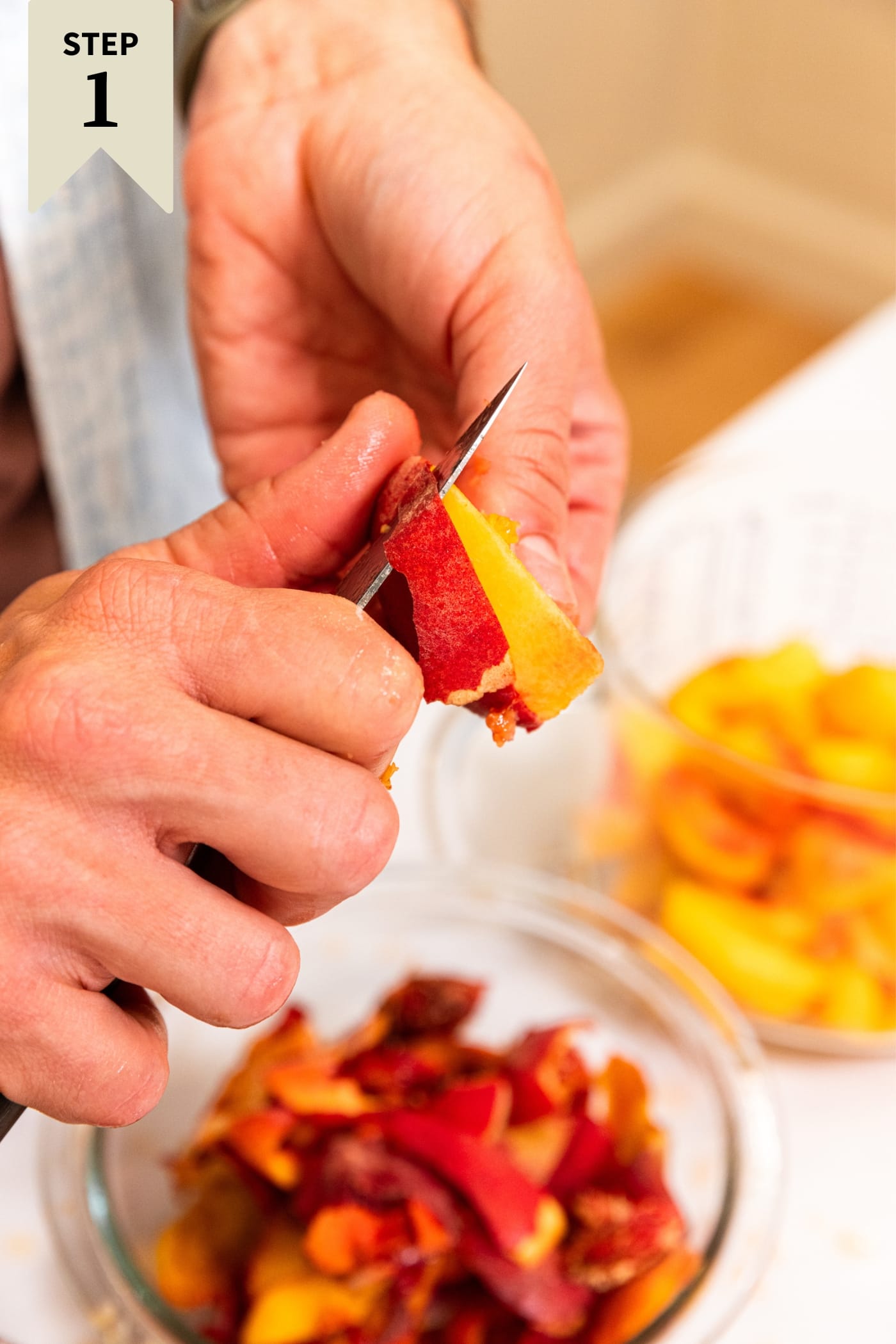 Hand using knife to peel a peach skin with bowl filled with discarded skin below.