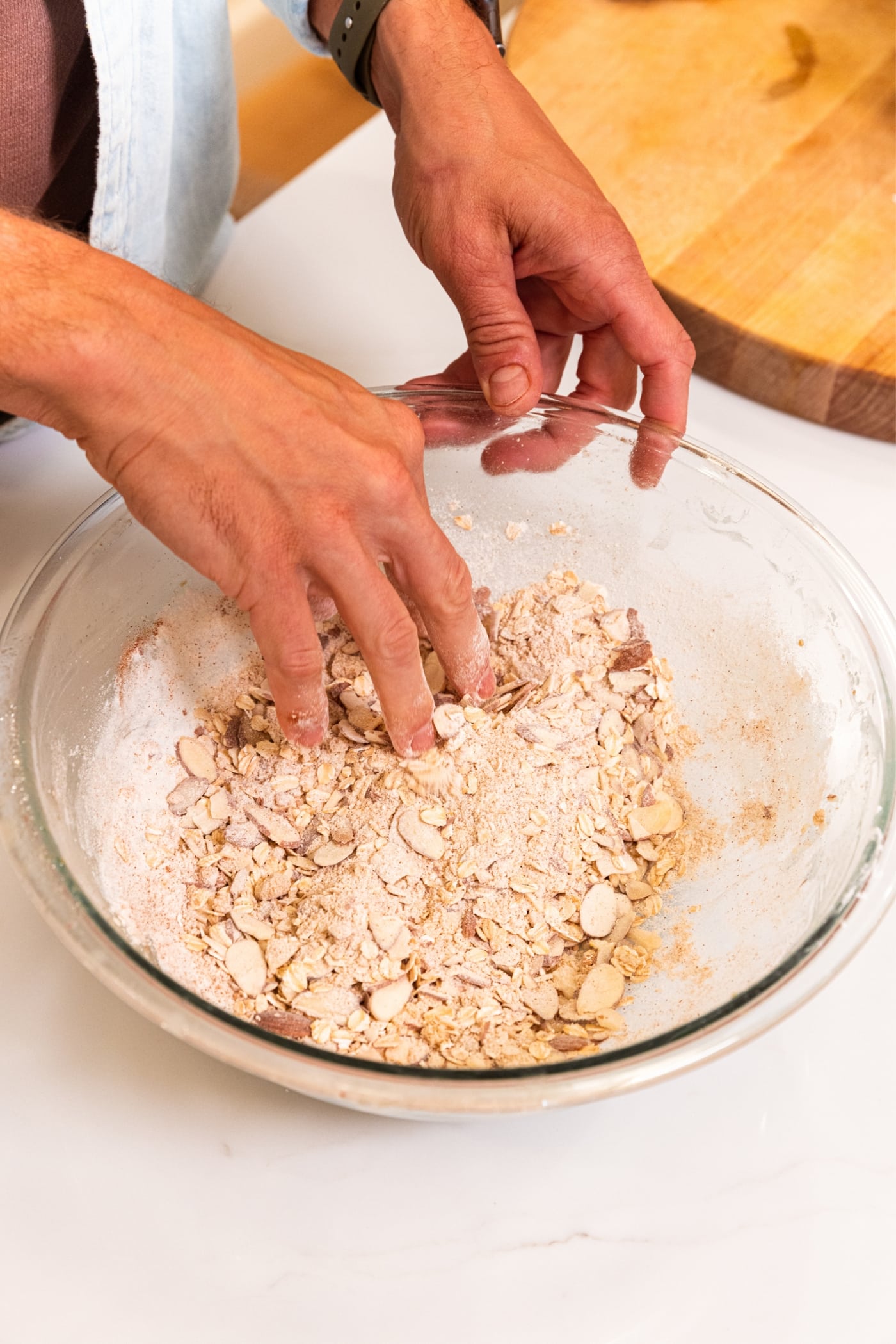 Hand mixing streusel ingredients together before adding butter with everything in a glass mixing bowl.