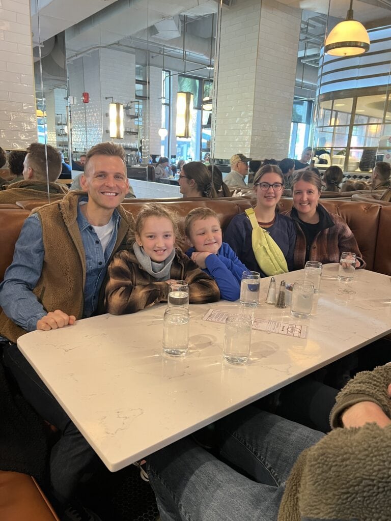 Kaleb Wyse wearing brown vest eating lunch with family members sitting at a table in a restaurant.