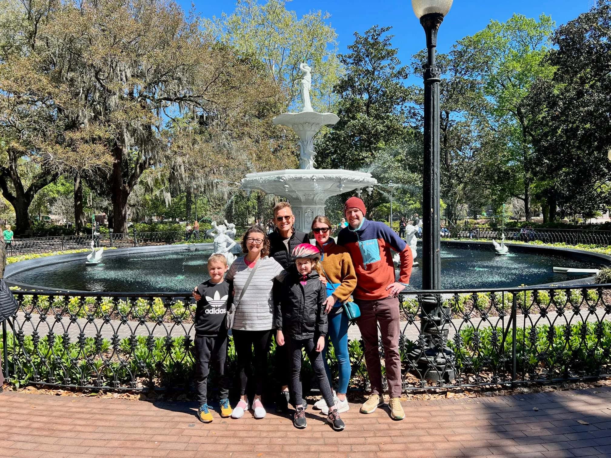 Kaleb Wyse with lots of family members standing in front of a fountain in a park taking group picture.