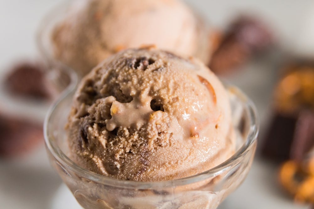 A scoop of chocolate brownie ice cream sits in a glass container.