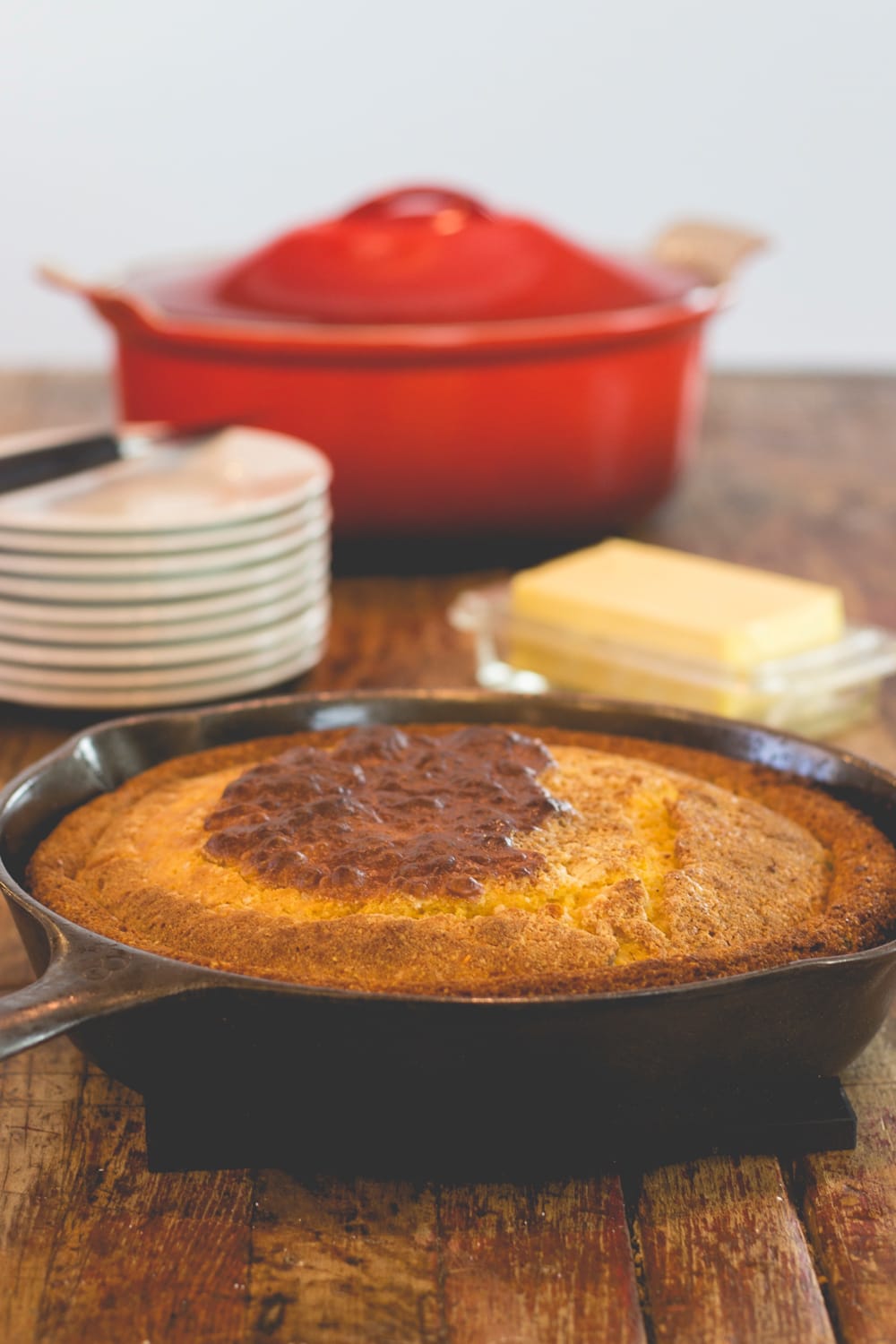 A skillet with cornbread sits on a wooden table.