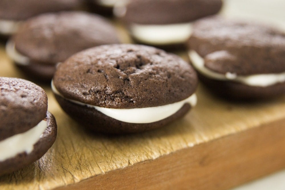 Cream-filled chocolate cookies sit on a wooden table.
