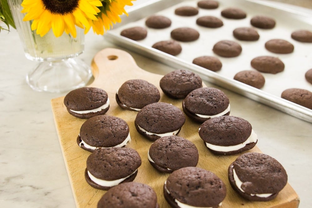 Rows of chocolate sandwich cookies line a wooden serving block.