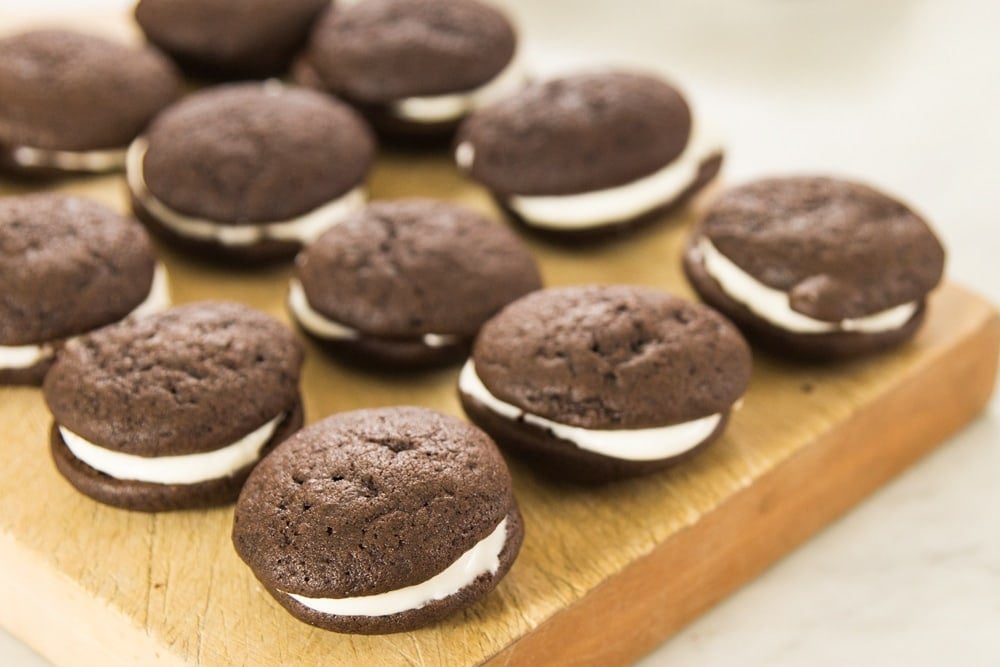 A grid of chocolate sandwich cookies sits on a wooden block.