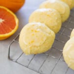 Cookies rest on a cooking rack next to oranges.