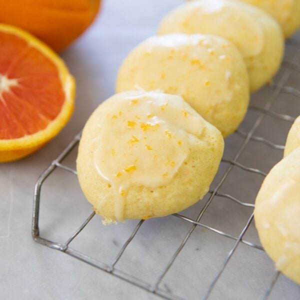 Cookies rest on a cooking rack next to oranges.