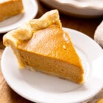 A slice of pumpkin pie sits on a plate.