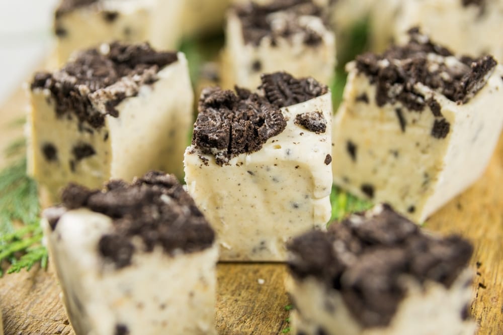 A piece of fudge is surrounded by other pieces on a serving block.
