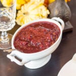 Cranberry sauce in a decorative dish rests on a table.