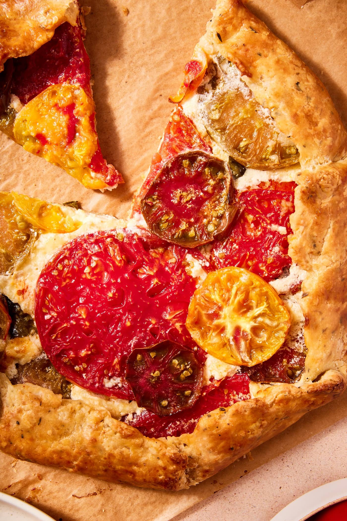 Baked tomato galette with golden brown crisped tomatoes with crispy crust all on piece of parchment.