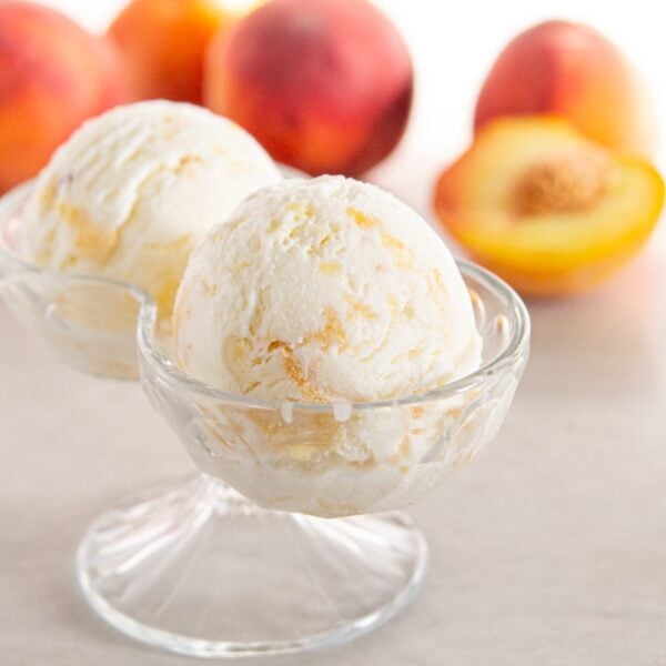 Two scoops of peach frozen yogurt rest in a decorative glass dish.