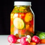 A jar full of pickled vegetables sits on a table.