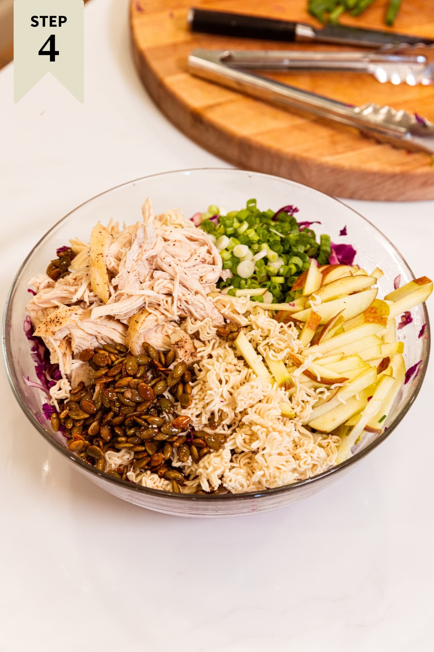 Large glass bowl filled with all components needed for ramen chicken salad.