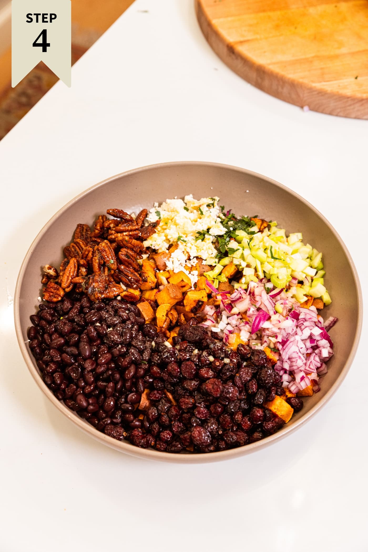 All components needed for a sweet potato salad resting in a large brown bowl before being mixed together.