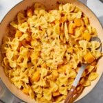Large pot filled with cooked pasta and butternut squash with spoon resting against the side of the pot.