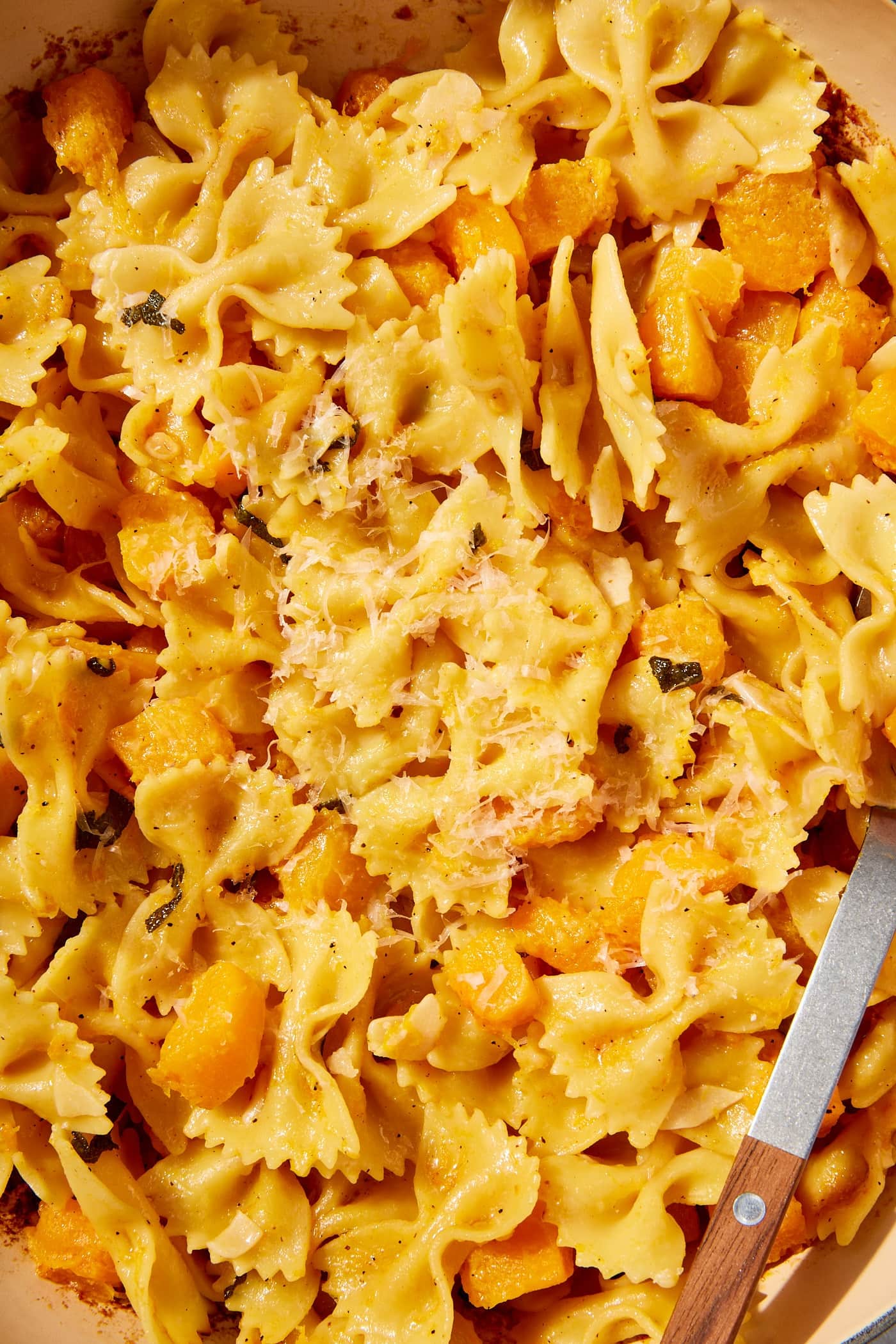 Cooked pasta with cooked cubed butternut squash sprinkled with herbs and Parmesan cheese.