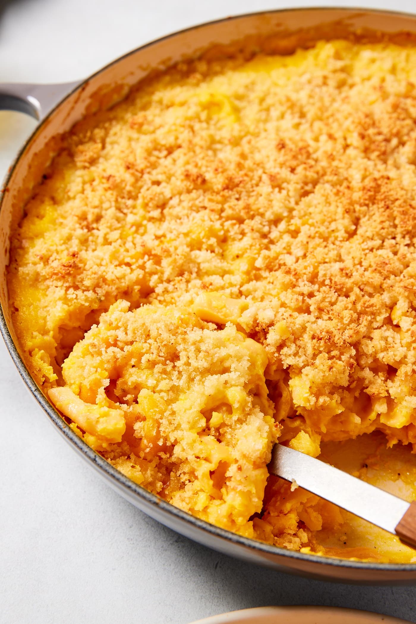 Large gray pot filled with cooked creamy butternut squash pasta with spoon scooping up a serving of the pasta.