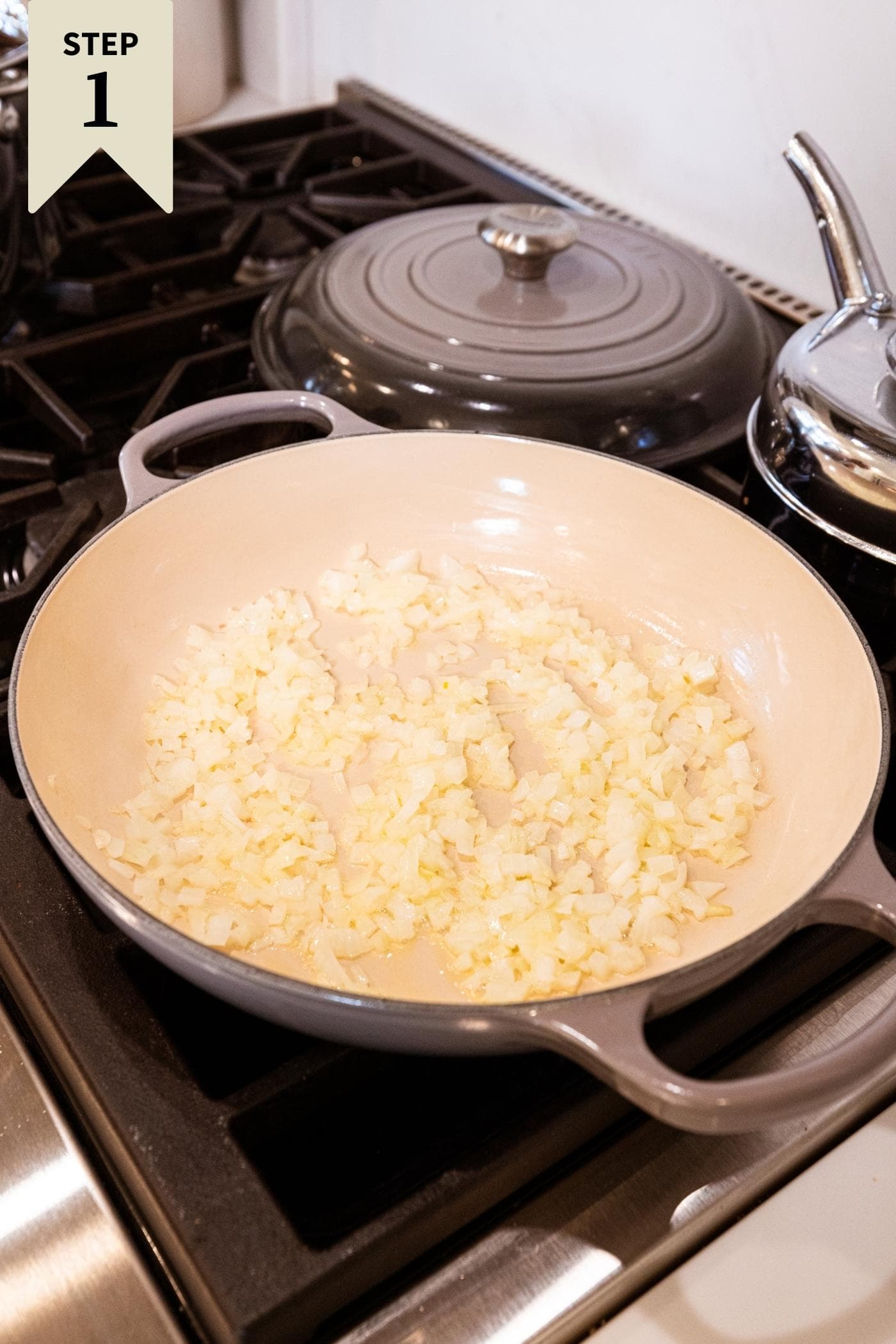 Large pot on stovetop with diced onion cooking to be browned.